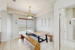 A dining area with a wooden table and benches, a hanging light fixture, and a door leading to another room. - Scenic Riverfront Home With Boat Access, Private Pool/hot Tub - Close to Shopping (Leander)