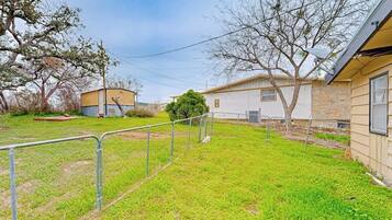 A fenced yard with a small building, a tree, and a utility pole.