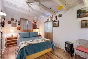 A bedroom with a bed, bedside tables, a lamp, a chair, a small table with a heater, and a ceiling fan. - Cozy Dog-friendly House Near Water With Enclosed Yard, Grill, & Equipped Kitchen (Burnet)