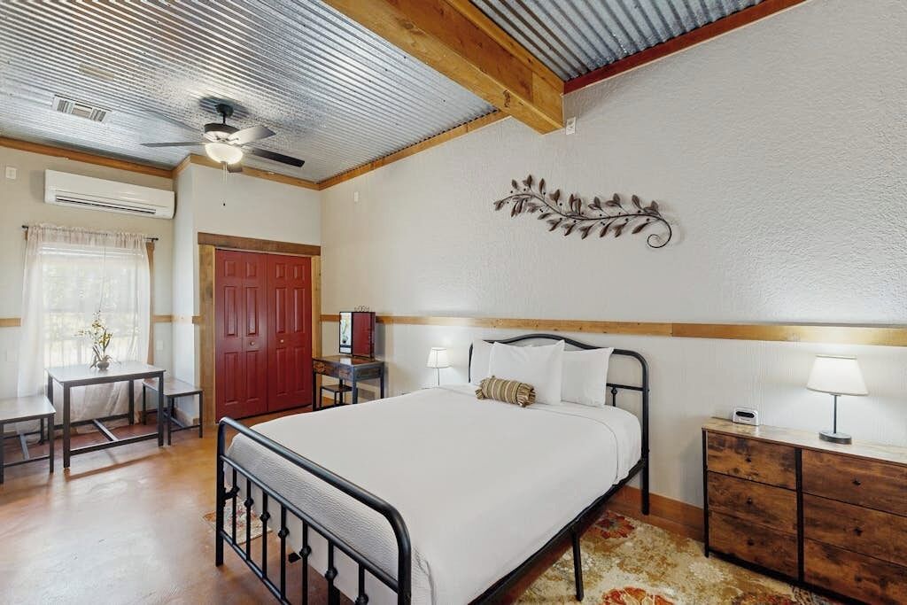 A bedroom with a bed, bedside tables, a desk, a chair, a wardrobe, and a ceiling fan.