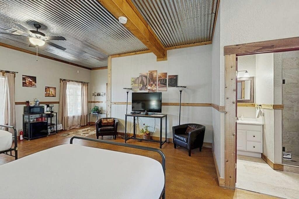 A room with a bed, a television, a desk, and a bathroom visible through an open door.