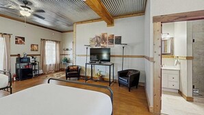 Una habitación con cama, televisión, escritorio y baño visible a través de una puerta abierta.