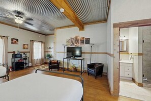 Ein Zimmer mit einem Bett, einem Fernseher, einem Schreibtisch und einem durch eine geöffnete Tür einsehbaren Badezimmer.