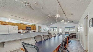 A spacious kitchen with wooden cabinets, a large island, and a long dining table with chairs. - Spacious Lakefront Home With Water Views, Wifi & Private Washer/dryer (Kingsland)