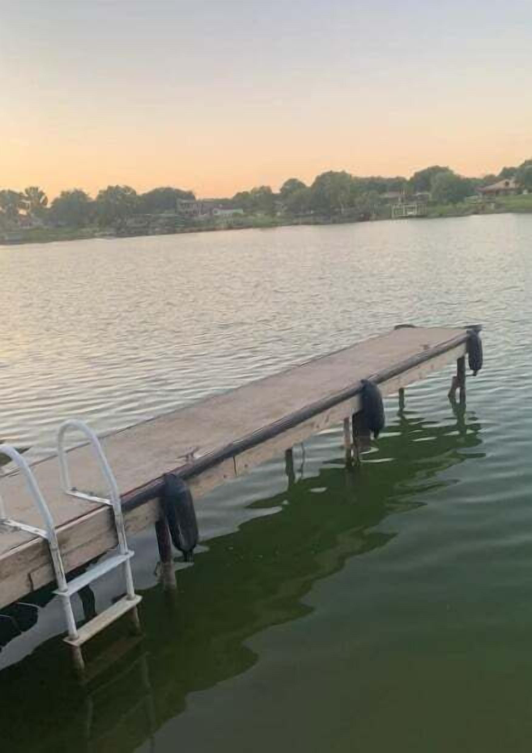Un muelle de madera se adentra en un cuerpo de agua tranquilo, con un horizonte despejado al fondo.