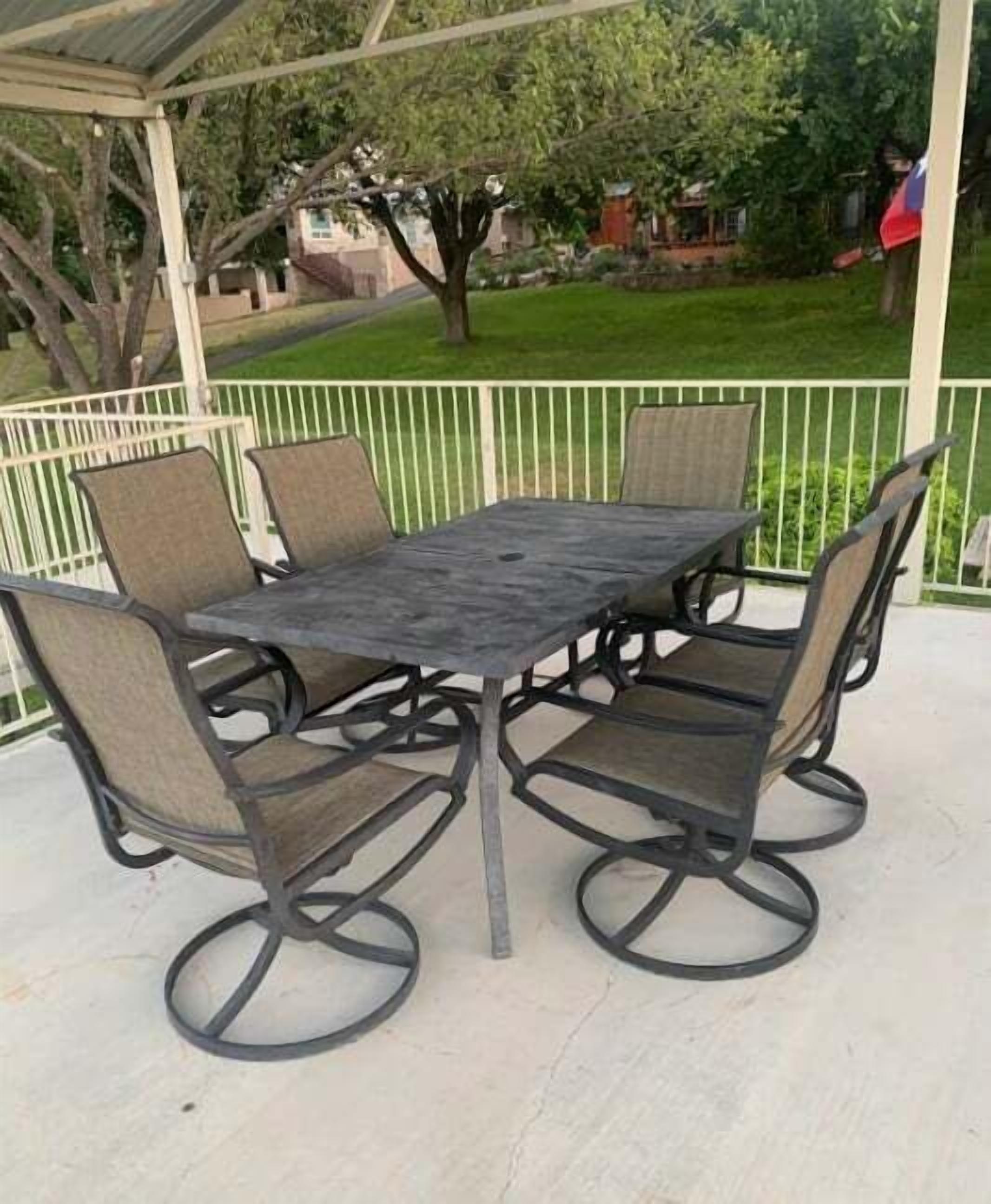 A covered patio with a metal table and four chairs.