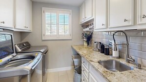 A kitchen with white cabinets, a stainless steel sink, a built-in oven, and a window with blinds. - Waterfront, Dog-friendly Home With Lake Views, Private Boat Lift & Dock (Horseshoe Bay)