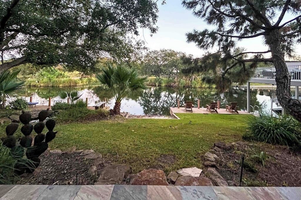 A landscaped garden with a pond, seating area, and a view of a building.