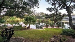 A landscaped garden with a pond, seating area, and a view of a building. - Waterfront, Dog-friendly Home With Lake Views, Private Boat Lift & Dock (Horseshoe Bay)