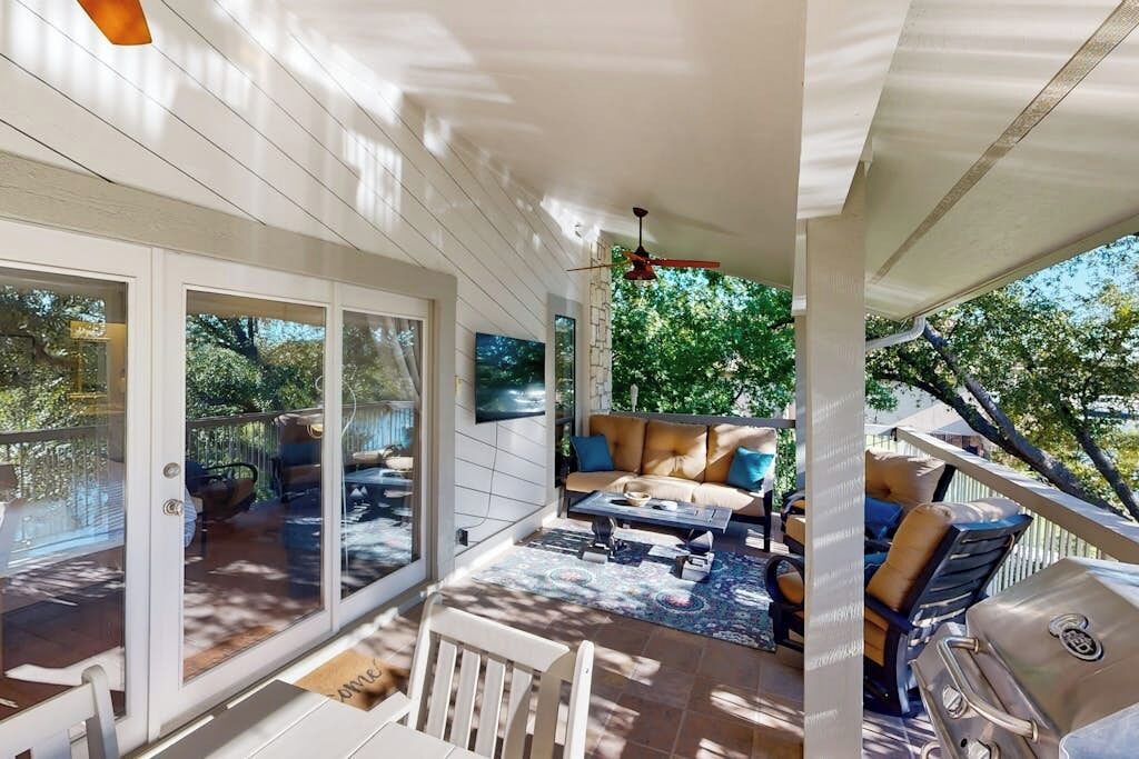 A covered patio with a seating area, a grill, and a view of the outdoors.