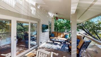 A covered patio with a seating area, a grill, and a view of the outdoors.