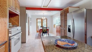 A kitchen with a granite countertop, stainless steel appliances, and a dining area with a chandelier. - Snowbird-friendly Home With Enclosed Yard, Firepit, Central AC, & High-speed Wifi (Fredericksburg)