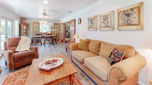 A living room with a sofa, armchair, coffee table, and artwork on the wall. - Snowbird-friendly Home With Enclosed Yard, Firepit, Central AC, & High-speed Wifi (Fredericksburg)