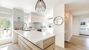 A modern kitchen with white cabinetry, a large island, and a pendant light. - 9 'Noosa Moorings' 303 Gympie Terrace Noosaville (Noosaville)