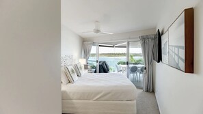 A bedroom with a bed, a ceiling fan, and a view of the sea through a sliding glass door. - 9 'Noosa Moorings' 303 Gympie Terrace Noosaville (Noosaville)
