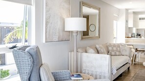 Een moderne woonkamer met een bank, een fauteuil, een vloerlamp en kunstwerken aan de muur.