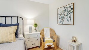 A bedroom with a bed, bedside table, lamp, chair, and a wall-mounted painting. - Peaceful, Modern Home Close to Lago Vista With Large Deck & Balcony (Marble Falls)