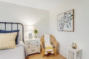 A bedroom with a bed, bedside table, lamp, chair, and a wall-mounted painting. - Peaceful, Modern Home Close to Lago Vista With Large Deck & Balcony (Marble Falls)