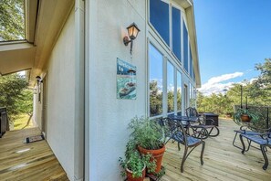 Eine überdachte Terrasse mit Holzboden, Metallstühlen und Blumentöpfen.