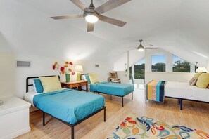Ein Schlafzimmer mit zwei Betten, einem Deckenventilator, einem Fenster und Blick ins Freie.
