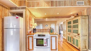 A kitchen with wooden paneling, a refrigerator, a stove, and a cabinet. - Historic Farmhouse With Lush Covered Patio - Near Wineries & Main St (Fredericksburg)