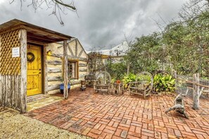 Eine rustikale Holzhütte mit gelber Tür, einer Ziegelterrasse und Gartenmöbeln.