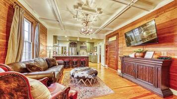 A spacious living room with a leather sofa, ottoman, and a large wooden cabinet with a flat-screen TV.