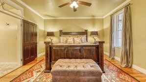 A bedroom with a wooden bed, a ceiling fan, a window with curtains, and a patterned rug. - Three Lovely Homes, Group- Family-friendly, Near Downtown, 2 Dogs OK (Fredericksburg)