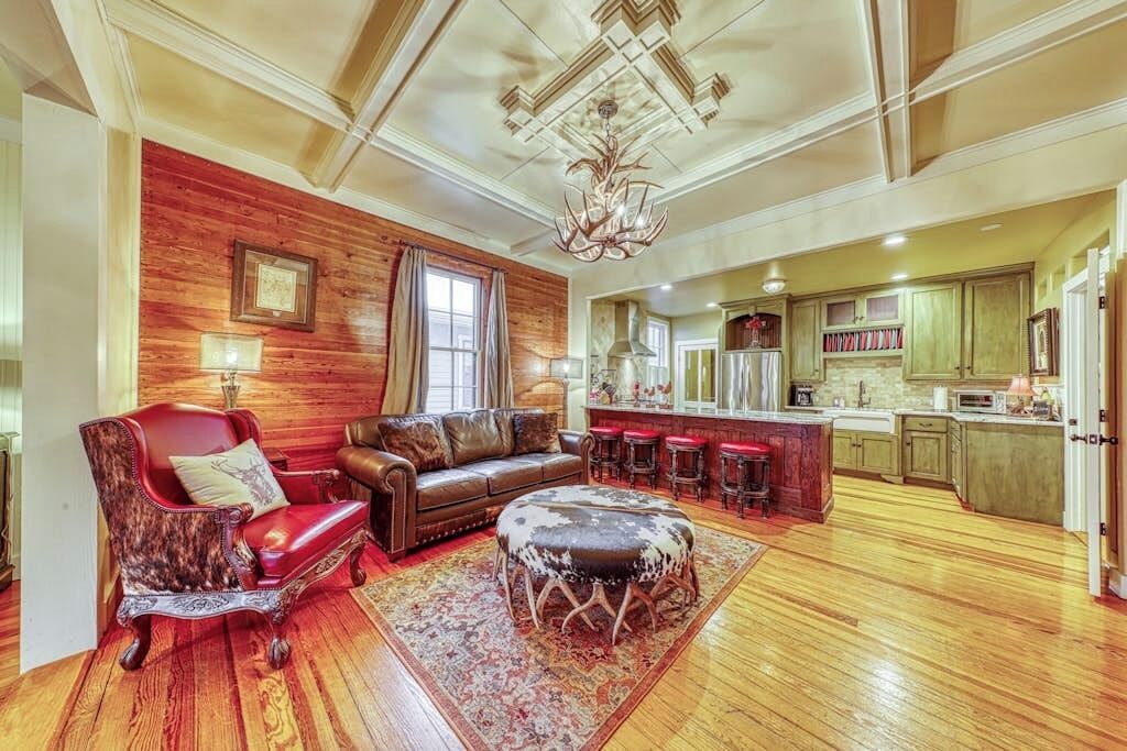 A spacious living room with a fireplace, leather furniture, and a kitchen area with bar stools.