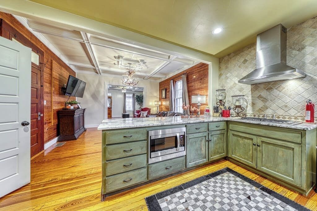 A kitchen with wooden cabinets, a large island, and a stainless steel range hood.