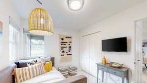 A modern bedroom with a bed, bedside table, and a television mounted on the wall. - Peaceful Mid-century Escape With Screened Porch & Lake Access (Leander)