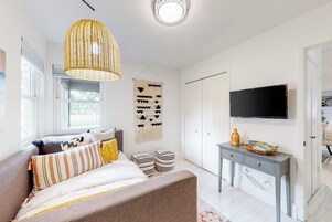 Un dormitorio moderno con cama, mesita de noche y televisor montado en la pared.