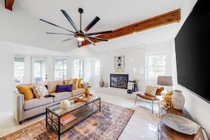 A modern living room with a sofa, coffee table, and fireplace. - Peaceful Mid-century Escape With Screened Porch & Lake Access (Leander)
