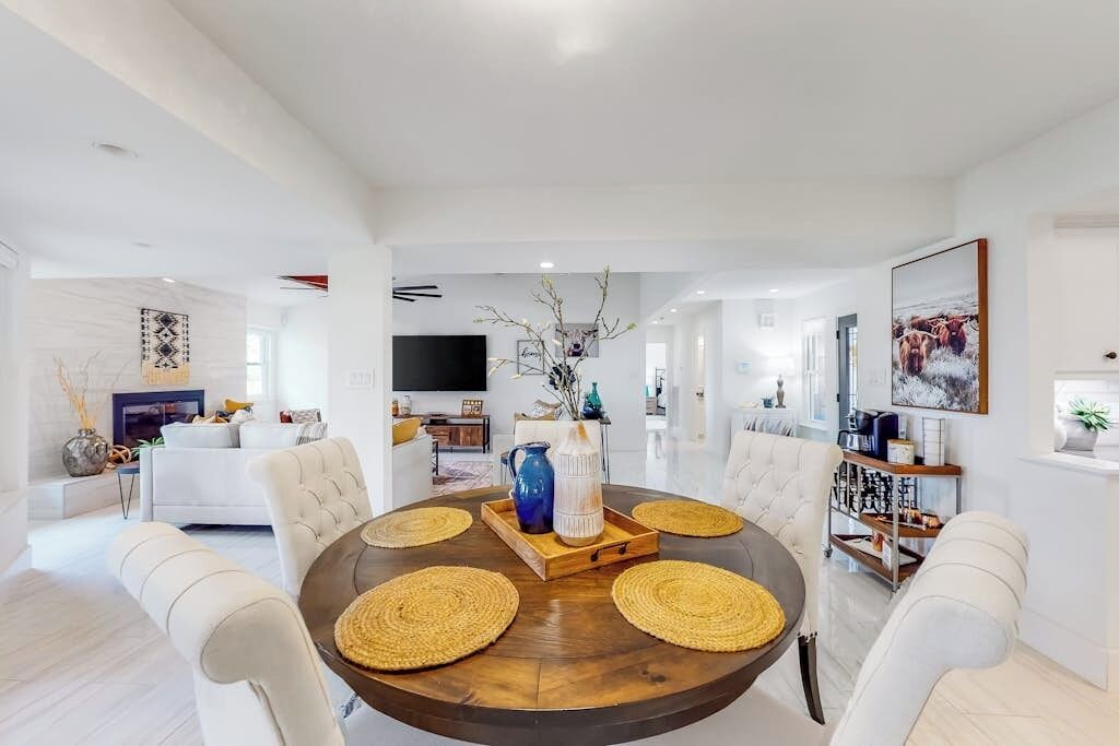 Un comedor moderno con una mesa redonda, sillas blancas tapizadas y un elemento decorativo central.