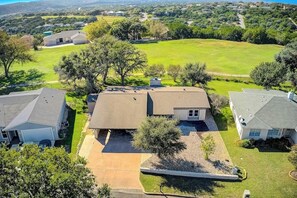 A residential area with houses, a large lawn, and a clear sky. - Peaceful Mid-century Escape With Screened Porch & Lake Access (Leander)