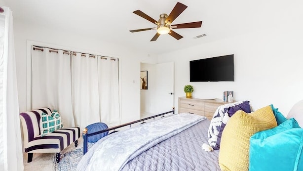 A bedroom with a bed, a ceiling fan, a TV, a chair, and a dresser. - Peaceful Mid-century Escape With Screened Porch & Lake Access (Leander)