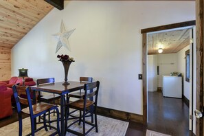 Un comedor con una mesa y sillas de madera, un adorno con forma de estrella en la pared y un sofá rojo al fondo.