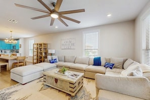 A spacious living room with a ceiling fan, a sofa set, a coffee table, and a kitchen in the background. - Stunning Lakefront Home on Lake LBJ With Private Balconies - Close to Yacht Club (Horseshoe Bay)