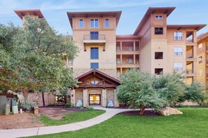 A multi-story building with a central entrance, balconies, and a landscaped courtyard. - Stunning Lakefront Home on Lake LBJ With Private Balconies - Close to Yacht Club (Horseshoe Bay)