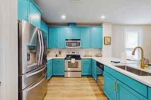 A kitchen with teal cabinets, stainless steel appliances, and a white countertop. - Stunning Lakefront Home on Lake LBJ With Private Balconies - Close to Yacht Club (Horseshoe Bay)