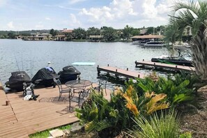 A dock with a table and chairs, a grill, and a tent by a lake with boats in the background. - Condo Near Lake Horseshoe Bay With Private Balcony, Washer/dryer, A/c, Wifi (Horseshoe Bay)