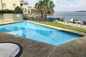A rectangular swimming pool with a metal fence, a palm tree, and a view of the water body in the background. - Condo Near Lake Horseshoe Bay With Private Balcony, Washer/dryer, A/c, Wifi (Horseshoe Bay)