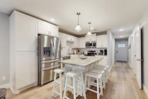 A modern kitchen with white cabinetry, stainless steel appliances, and a central island with bar stools. - Condo Near Lake Horseshoe Bay With Private Balcony, Washer/dryer, A/c, Wifi (Horseshoe Bay)