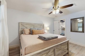 A bedroom with a bed, a ceiling fan, a nightstand, a mirror, and a walk-in closet. - Condo Near Lake Horseshoe Bay With Private Balcony, Washer/dryer, A/c, Wifi (Horseshoe Bay)