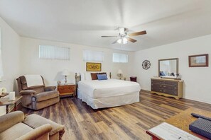 Ein Schlafzimmer mit einem Bett, zwei Stühlen, einem Schminktisch und einem Deckenventilator, sowie einem Fenster.