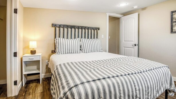 Un dormitorio con cama, mesita de noche, lámpara y una puerta.