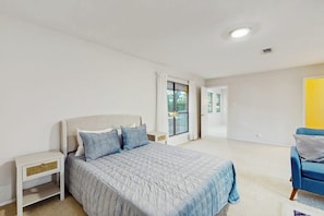 A bedroom with a bed, nightstands, a chair, and a door leading to a balcony. - Cozy Dog-friendly Home With Full Kitchen, Patio & Backyard, Close to Golf Course (Horseshoe Bay)