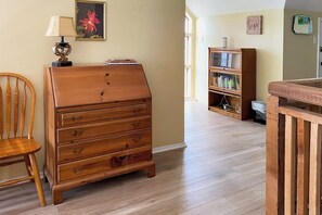 Une pièce comprenant une commode en bois, une chaise, une bibliothèque et une rambarde en bois.