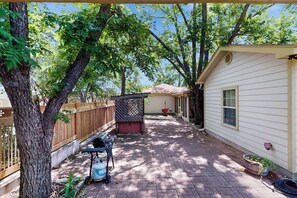 A backyard with a wooden fence, a barbecue grill, and a shed. - Cozy & Cute Cabin With Fenced Patio, Grill, AC & Wifi - Walkable Locale (Fredericksburg)