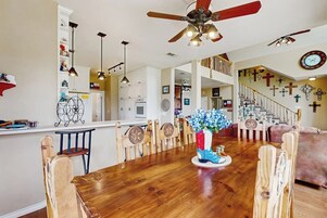 Una cocina amplia con armarios de madera, un comedor con mesa y sillas de madera, y una escalera que conduce a un nivel superior.